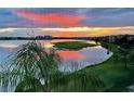 Scenic lake view reflecting a vibrant sunset with lush greenery and waterfront buildings, creating a serene atmosphere at 6450 Watercrest Way # 402, Lakewood Ranch, FL 34202