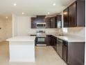 Modern kitchen featuring dark wood cabinets, stainless steel appliances, and a spacious island at 17384 Robinson Ave, Port Charlotte, FL 33948