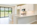 Modern kitchen features white cabinets, quartz countertops, stainless steel appliances and sliding door to backyard at 18324 Rockport Pl, Lakewood Ranch, FL 34211