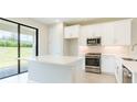 Contemporary kitchen boasts white cabinetry, stainless steel appliances, and an island with breakfast bar seating at 18324 Rockport Pl, Lakewood Ranch, FL 34211