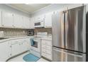 Efficient kitchen with white cabinets, stainless steel appliances, and mosaic backsplash at 25188 Marion Ave # A103, Punta Gorda, FL 33950