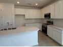 Contemporary kitchen featuring white cabinetry, stainless appliances, and tile backsplash at 9613 Vibrant Lane, Venice, FL 34292