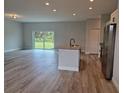 Open concept kitchen with island, stainless steel appliances, and grey vinyl flooring at 7137 Benson St, Englewood, FL 34224