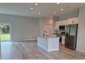 Open concept kitchen with island, stainless steel appliances, and grey vinyl flooring at 7137 Benson St, Englewood, FL 34224