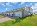 Row of townhomes featuring attached garages, brick driveways, and fresh landscaping on a sunny day at 17314 Alderwood Ln, Punta Gorda, FL 33982