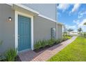 Stylish blue front door with brick pathway, complemented by lush green landscaping and a clear blue sky at 17314 Alderwood Ln, Punta Gorda, FL 33982