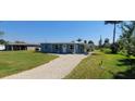 Quaint blue home with a gravel driveway and a well-manicured lawn at 3420 Ash St, Punta Gorda, FL 33950
