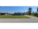 Cozy single-story blue home featuring a gravel driveway and a lush green lawn at 3420 Ash St, Punta Gorda, FL 33950