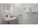 This half bathroom offers a modern sink and faucet, alongside white towels and an attractive, oval mirror at 12843 Buffalo Run Dr, Gibsonton, FL 33534