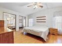Bright bedroom featuring wood laminate floors, natural light, mirrored closet doors, and ceiling fan at 35935 Tanda Cir, Zephyrhills, FL 33541