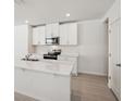 Modern kitchen boasts white cabinets, stainless steel appliances, and a large island at 113 Whiteland Bnd, Nokomis, FL 34275
