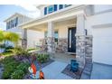 Front porch with stone columns and rocking chairs at 8493 Hardy Bay Loop, Wesley Chapel, FL 33545
