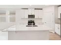 White kitchen with stainless steel appliances and an island at 180 Lazy Shore Dr, Nokomis, FL 34275