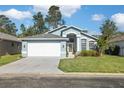 Light blue house exterior with white garage door and landscaping at 7940 Fashion Loop, New Port Richey, FL 34654