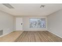 Bright living room featuring light wood-look flooring and a large window at 8018 Idle Briar Ln, Port Richey, FL 34668
