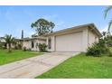 Single-story house with a white exterior, a driveway, and a well-maintained lawn at 8018 Idle Briar Ln, Port Richey, FL 34668