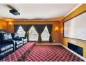 Home theater room complete with tiered seating, projector, screen, sconce lighting, and window with draped curtains at 11909 Mandevilla Ct, Tampa, FL 33626