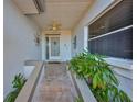 Charming covered front porch with neutral colored tile, complemented by decorative wall art and manicured plants at 903 Pinellas Bayway S # 302, Tierra Verde, FL 33715