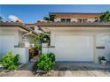 This townhome has a white garage door and a front facade framed by tropical landscaping and well maintained entryway at 903 Pinellas Bayway S # 302, Tierra Verde, FL 33715