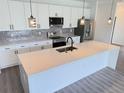 Modern kitchen with white cabinets, stainless steel appliances, and a quartz countertop island at 1074 Kacerik St, North Port, FL 34288