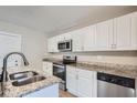 Modern kitchen with white cabinets, granite counters, and stainless steel appliances at 11335 Pickford St, Spring Hill, FL 34609