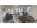 Open living and dining area with grey couches, brown table, and a large window at 11865 Sylvia St, Dade City, FL 33525