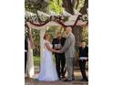 Couple exchanging vows under a floral wedding arch at 15625 State Road 62 St, Parrish, FL 34219