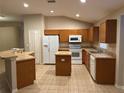 Kitchen with wood cabinets, white appliances and an island at 15838 Cedar Elm Ter, Land O Lakes, FL 34638