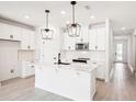 White kitchen with large island, stainless steel appliances, and black pendant lights at 104 Runaway Field Ave, Nokomis, FL 34275