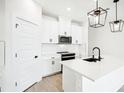 Modern white kitchen with black hardware, stainless steel appliances, and an island at 104 Runaway Field Ave, Nokomis, FL 34275