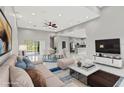 Bright, open concept living room with modern furniture and adjacent dining and kitchen areas at 5277 Epping Ln, Zephyrhills, FL 33541