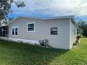 Side view of a tan mobile home with landscaping at 3145 Hidden Lake Dr, Wesley Chapel, FL 33543