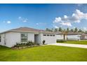 Exterior view of a single-story home with a gray garage door, landscaping, and a lush green lawn at 21104 Alpine Ave, Port Charlotte, FL 33952