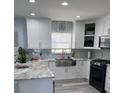 Modern kitchen with white cabinets, marble countertops, and a farmhouse sink at 5519 Turtle Crossing Loop, Tampa, FL 33625