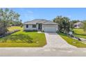 Beautiful new home with a dark metal roof, brick paved driveway, and a manicured lawn at 16760 Acapulco Rd, Punta Gorda, FL 33955