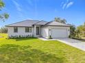Charming single-story home with well-manicured lawn, grey metal roof and paver driveway at 16760 Acapulco Rd, Punta Gorda, FL 33955