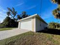 View of the side entry two-car garage with a brick paved driveway on a beautiful sunny day at 37 Warrington Blvd, Port Charlotte, FL 33954