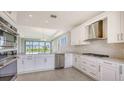 Open kitchen with stainless appliances, white cabinets, granite countertops, tile backsplash, and tile floors at 14370 Hammock Oak St, Parrish, FL 34219