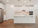 Bright, modern kitchen features white cabinets, stainless steel appliances and wood-look tile flooring at 466 Sun Chaser Dr, Nokomis, FL 34275