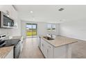 Bright kitchen features stainless steel appliances, white cabinets, and a granite island at 225 Lazy Shore Dr, Nokomis, FL 34275