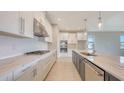 Modern kitchen showcasing white and grey cabinetry, stone countertops, and stainless steel appliances at 14517 Coastal Woodland Ln, Parrish, FL 34219