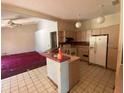 Kitchen featuring tile floors, an island, appliances, and access to an adjacent carpeted room with a ceiling fan at 18316 Oxenham Ave, Spring Hill, FL 34610