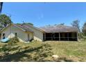 Back exterior view showcasing a long, covered patio, lush backyard, and an exterior door for easy access at 18316 Oxenham Ave, Spring Hill, FL 34610