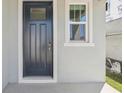 A close-up of a modern black front door with a window, complemented by gray siding and trim at 1852 Brekey Way, Zephyrhills, FL 33541