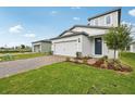 New construction home featuring a two-car garage, modern design, brick driveway, and landscaped front yard at 1868 Brekey Way, Zephyrhills, FL 33541