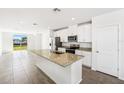 Open-concept kitchen with granite countertops, white cabinets, stainless appliances, and a central island sink at 1876 Brekey Way, Zephyrhills, FL 33541