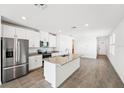 Bright kitchen features white cabinets, stainless steel appliances, and a large center island at 1876 Brekey Way, Zephyrhills, FL 33541