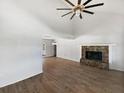 Open-concept living room with a stone fireplace, vaulted ceilings, hardwood floors, and an open view of the dining area at 4000 Barbary Ln, North Port, FL 34287