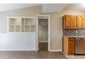 Open-concept kitchen with wooden cabinets, stainless steel dishwasher, and seamless flow to the next room at 7216 E Emma St, Tampa, FL 33610
