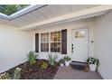 Inviting front porch featuring a white door, dark hardware, and manicured flower beds at 7746 Westmoreland Dr, Sarasota, FL 34243